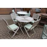 An octagonal shaped folding garden table with four folding chairs with cushions
