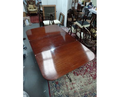 An early 19th century mahogany twin pillar D end dining table, fitted one additional leaf, the pillar supports on tripod swep