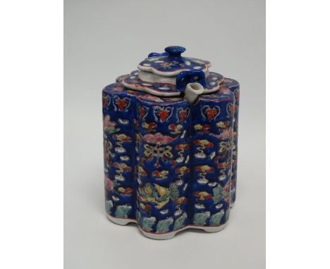 A Canton porcelain encased teapot of lobed form decorated in rich blue enamel and famille rose colours with garlands, calligr