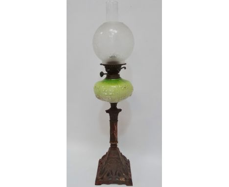 A late 19th century oil lamp with iron and copper patinated column support and opaque green glass reservoir and etched glass 