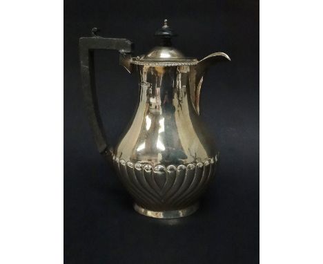 A silver hot water jug, the baluster body with gadrooned decoration with ebony finial and handle, Birmingham 1911, height 18.