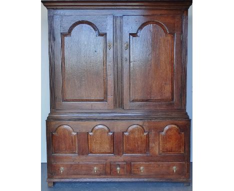 An 18th century oak housekeeper's cupboard, the upper section fitted arcaded panel doors with reeded carved decoration, the l
