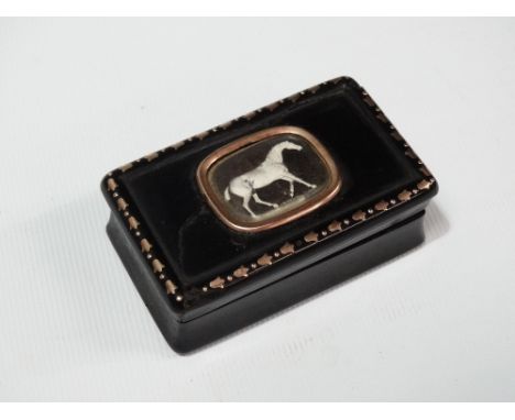 A Georgian ebony snuff box, the centre of the lid with yellow metal mount inset an Essex Crystal reverse carved horse, the bo