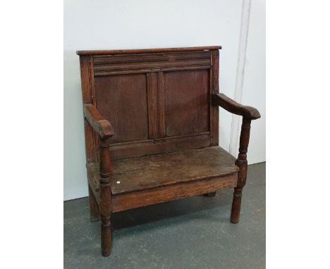 An early 18th century and later small panel back oak settle with turned supports and shaped arms, width 77cm. 