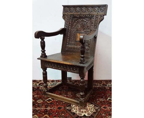 An early 17th century and later panel back open oak armchair, the back with arcaded carved and inlaid panel, the lower frame 