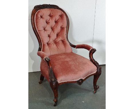A Victorian walnut framed salon armchair with carved frame and cabriole legs with brass and ceramic castors, buttonback and p