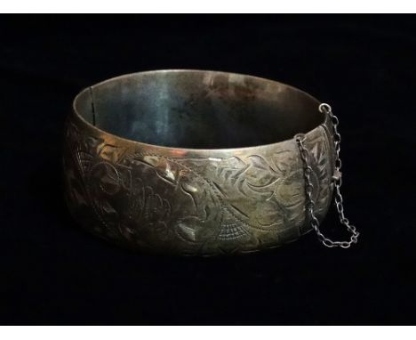 A sterling silver hinged bangle with engraved decoration, weight 49g.