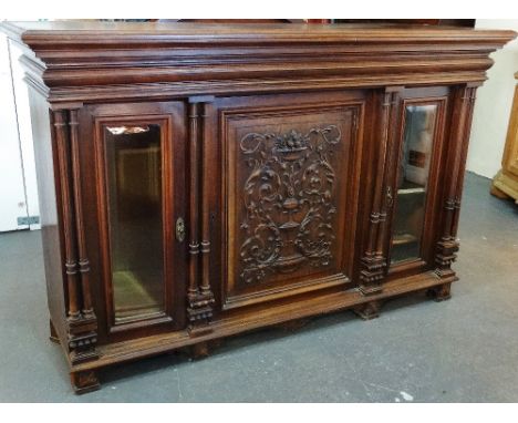 A French walnut side cabinet with central elaborately carved door flanked by two glazed cupboards with reeded pillar decorati