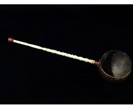 A late 19th century sailor's rum ladle, with coconut shell bowl and turned marine ivory stem, length 38cm.