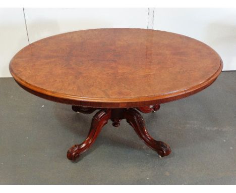 A mid 19th century walnut tilt top centre table with well figured oval top, turned and carved support on four cabriole carved