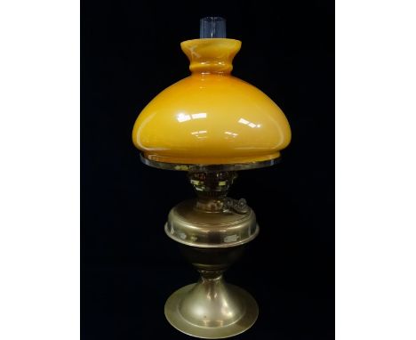 A brass oil lamp with an amber overlaid glass shade, height 50cm. 