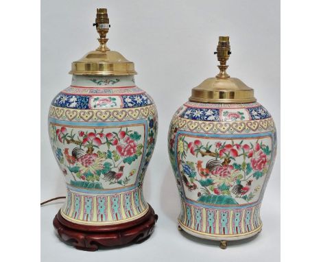 A near pair of Chinese porcelain famille rose lamp bases with brass and wood fittings, decorated with panels of flowering tre