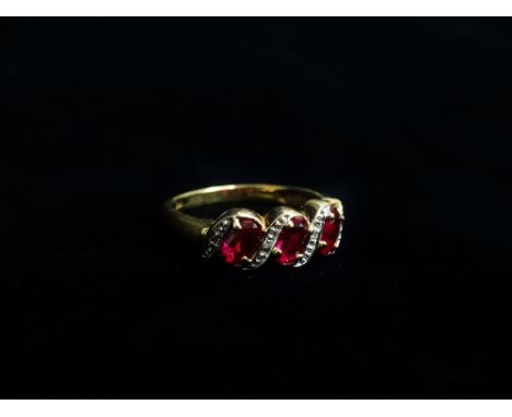 A 9ct gold dress ring set three red stones and diamond chips, size L.