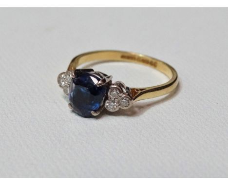 An 18ct white and yellow gold ring set a central sapphire flanked by six diamonds in a clover leaf style setting, size R/S.