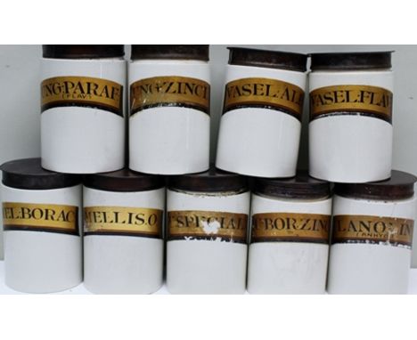 A COLLECTION OF NINE EARLY 20TH CENTURY GLAZED POTTERY CHEMIST JARS, with gilded panel, script titles, each with a tin cover,