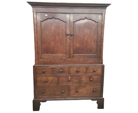 19th century oak linen press, the cavetto moulded cornice above two shaped panelled doors opening to reveal shelves, on a bas