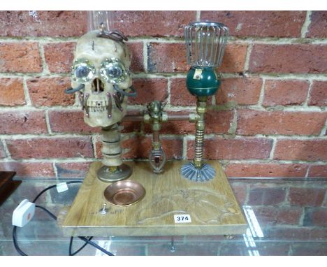AN UNUSUAL STEAM PUNK THEMED DESK LAMP WITH CARVED BASE AND ILLUMINATING SKULL.