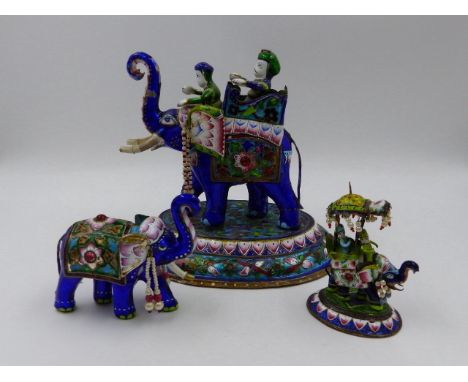 THREE INDIAN ENAMEL AND SILVERED FIGURES OF ELEPHANTS, TWO WITH HOWDAHS AND RIDERS.   LARGEST H.16.5cms.