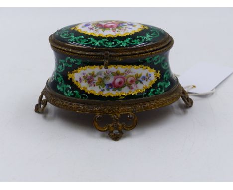 A VICTORIAN FRENCH ENAMEL OVAL DRESSER BOX WITH PIERCED BRASS MOUNTS AND POLYCHROME FLORAL SPRAYS ON A SCROLL DECORATED GREEN