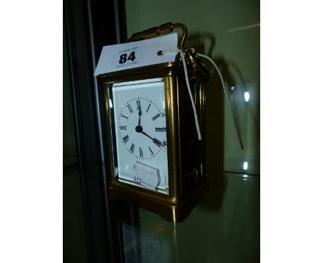 A BRASS CASED CARRIAGE CLOCK WITH A WHITE ENAMEL DIAL COMPLETE WITH KEY.   H.14cms.