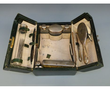 An Edward VII leather cased travelling vanity case fitted with five hallmarked silver topped bottles, two brushes, button hoo