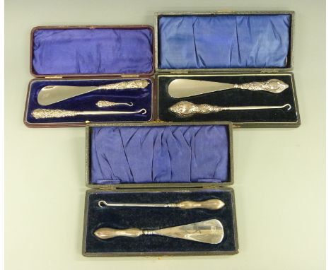 Three cased hallmarked silver handled button hook / shoe horn sets, Birmingham 1900, Chester 1911 and Chester 1915