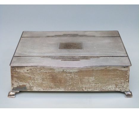 An Art Deco hallmarked silver cigarette box with engine turned decoration, raised on four feet, Birmingham 1940 maker William