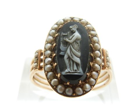 An early Victorian ring set with a hardstone cameo depicting a woman playing the harp, surrounded by seed pearls, size O/P, 3