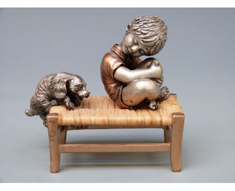 A novelty white metal or similar and bronzed model of a boy and a dog on a rush seated stool, marked to boy 800, possibly Ita