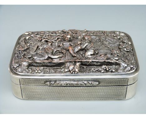 A continental white metal engine turned cigarette or similar dressing table box with plated relief lid depicting cherubs, gil