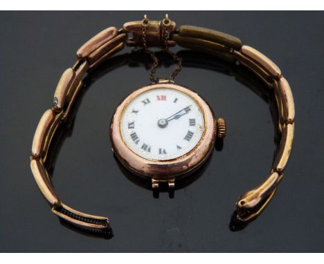 A 9ct gold ladies wristwatch with black hands and Roman numerals, gilt dot minute markers, white enamel face and Swiss moveme