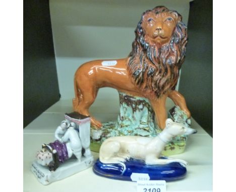 A 19thC Staffordshire model of a greyhound lying down with its front paws crossed, on a blue base, 8cm tall together with a l