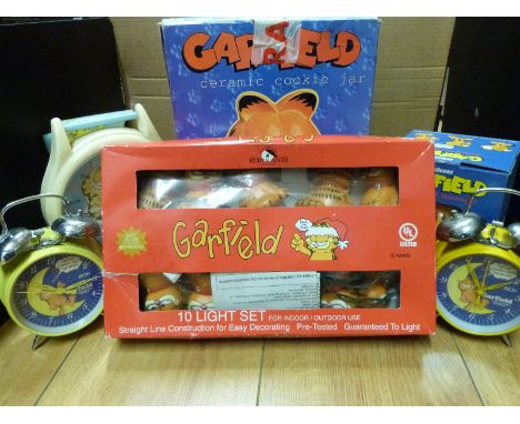 A boxed Garfield ceramic cookie jar together with Garfield alarm clocks, giant watch, Christmas lights and a Garfield massage