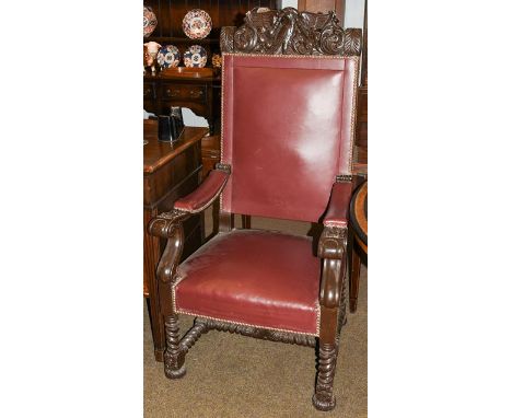 WWII Interest: A heavily carved boardroom armchair with studded leather upholstery, the deep cresting rail carved with a styl