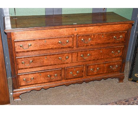 A George III oak Lancashire chest crossbanded in mahogany, with reeded moulding and raised on ogee bracket supports, 148cm by