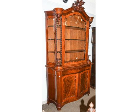 A Biedermeier mahogany serpentine display cabinet, with carved pediment, twist supports and raised on ogee bracket feet, 120c