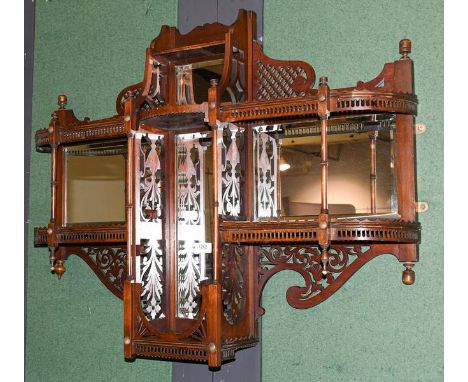 A Victorian mahogany mirror backed two-tier hanging wall shelf, with swan neck pediment, openwork carving and turned supports