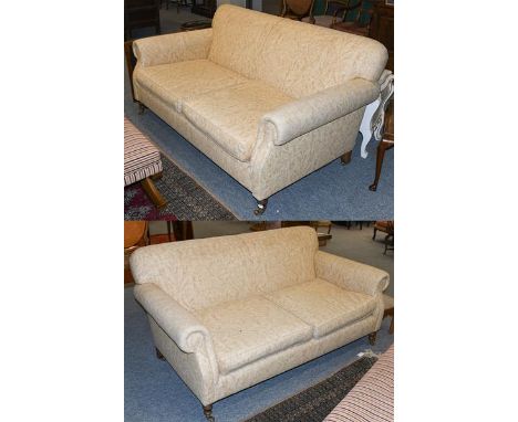 A pair of cream upholstered three seater sofas, with scroll arms and moving on castors, 185cm by 100cm by 90cm.  Each sofa wi