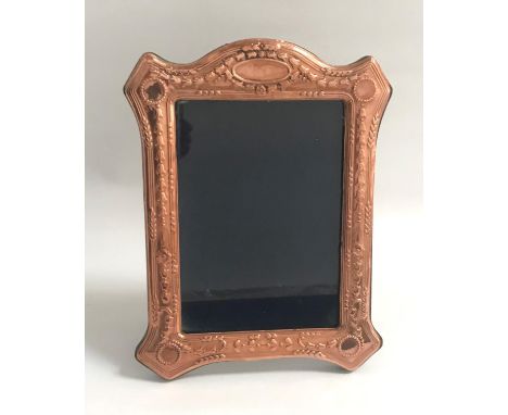 EDWARDIAN STYLE COPPER PHOTOGRAPH FRAMEthe shaped frame with relief floral decoration, on easel support, 24cm high 