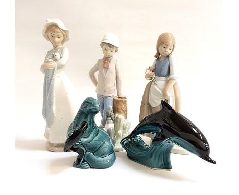 THREE NAO FIGURINEScomprising a young boy with his, dog, 23cm high; a girl in a bonnet holding a puppy, 25cm high; and a youn