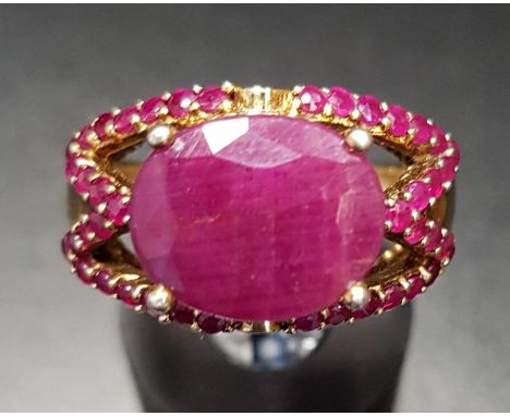 RUBY DRESS RINGthe large central oval cut ruby flanked by ruby set split shoulders, on silver gilt shank, ring size L-M 