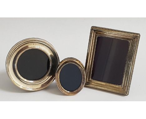 THREE SILVER PHOTOGRAPH FRAMEScomprising a rectangular example, 11.2cm high; a circular example, 9.2cm diameter; and an oval 