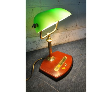 A BRASS BANKERS LAMP, with a green adjustable shade, on a wooden base fitted with a pen tray