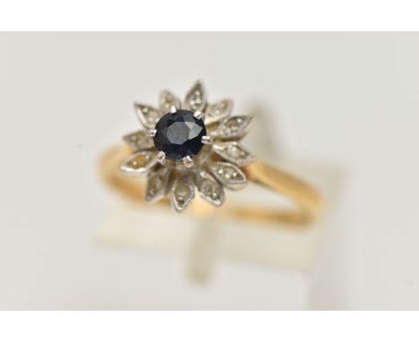 AN 18CT YELLOW GOLD CLUSTER RING, flower shape cluster set with a raised circular cut deep blue sapphire, in a surround of pe