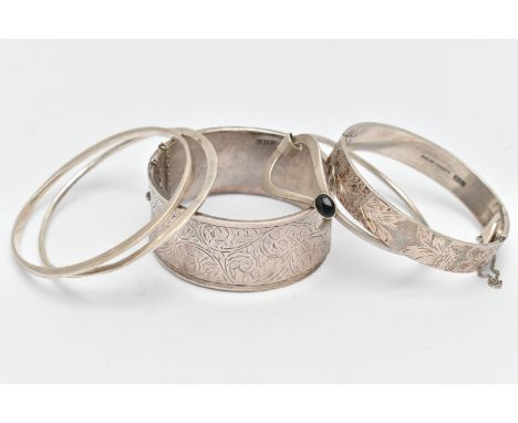 THREE SILVER BANGLES AND TWO WHITE METAL BANGLES, the first a silver wide hinged bangle, with scrolling acanthus detail, appr