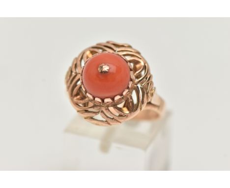 A YELLOW METAL CORAL RING, set with a raised coral cabochon with pin to the centre, in a claw setting to the open work circul