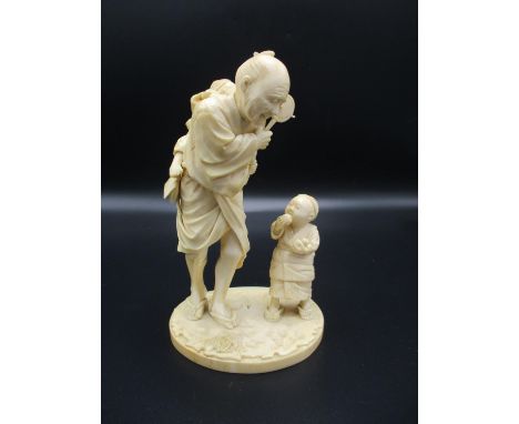 A Japanese Meiji period ivory okimono, modelled as an elderly man with children, one on his back playing, the other holding f