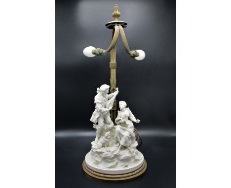 An early 20th century Continental Parian twin lamp, probably French Belle Epoque, modelled with a Watteau-esque couple, the g
