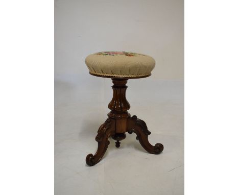 Victorian rosewood circular music stool having revolving height adjustable seat, raised on three carved scroll legs  