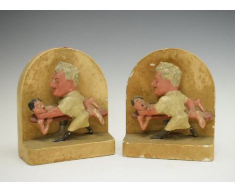 Pair of ceramic World War II themed book ends showing Adolf Hitler being stretched and strangled by Medical personnel, signed